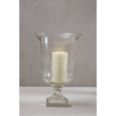 Clear glass hurricane lamp with a candle on a gray background