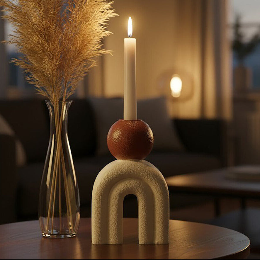 Decorative candle with a vase of dried pampas grass on a table in a softly lit room.