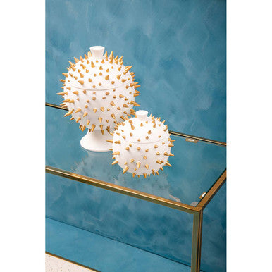 Decorative white and gold spiky spheres on a glass table with a blue background