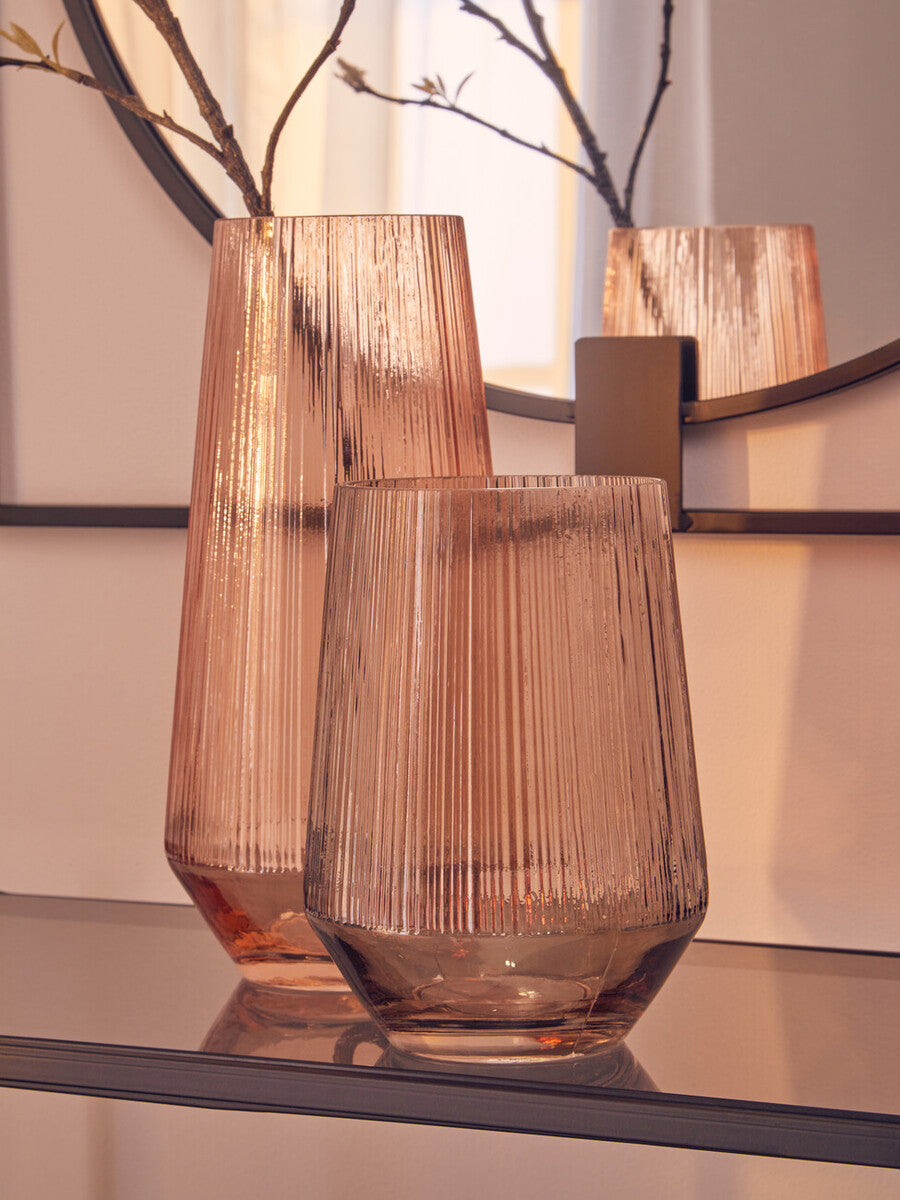 Two brown glass vases on a reflective surface with a blurred background