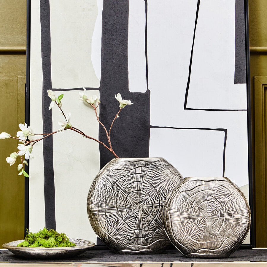 Decorative tree stump plates on a wooden surface with a abstract art piece in the background.
