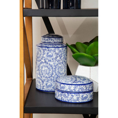 Blue and white ceramic jars on a black shelf with a plant in the background