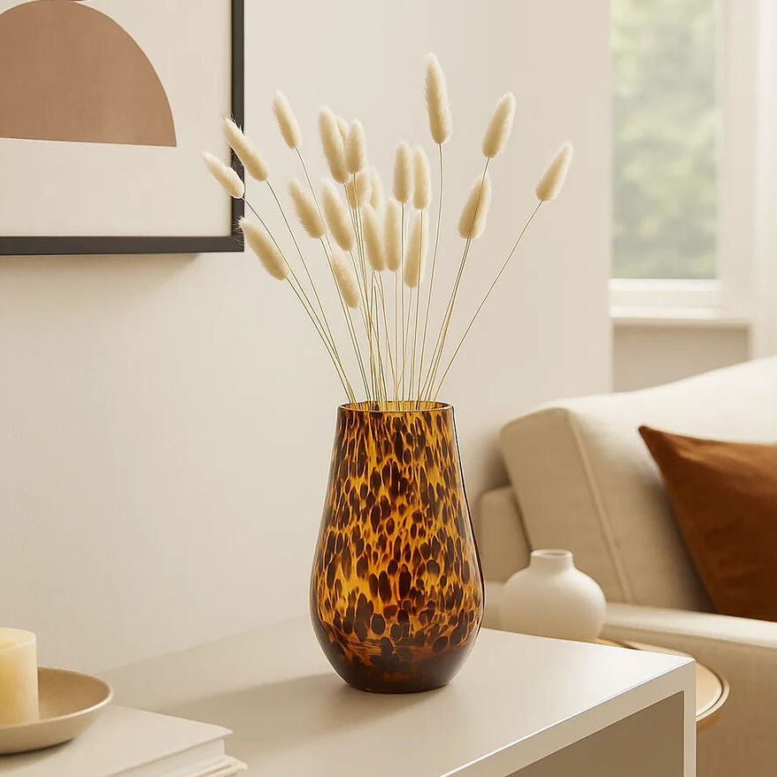Decorative vase with dried plants on a coffee table in a living room.