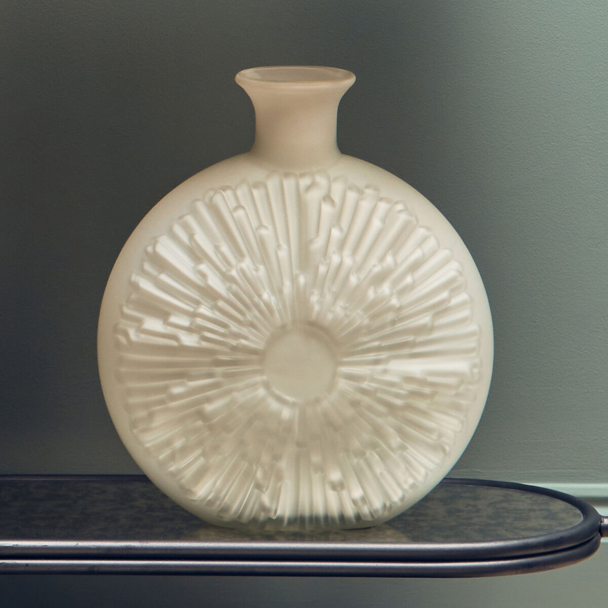 Beige ceramic vase with textured design on a dark surface against a gray background