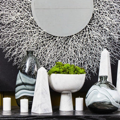 Decorative shelf with vases, candles, and a bowl against a textured wall.