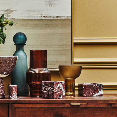 Decorative items including vases and bowls on a wooden surface with a gold cabinet in the background.