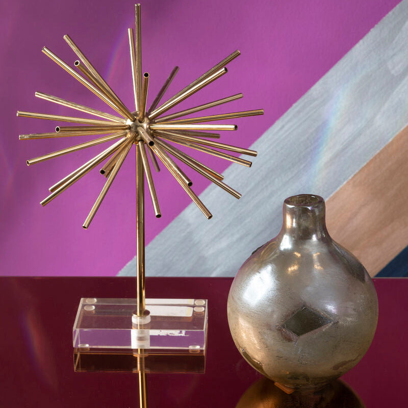 Decorative metallic star-like object on a stand with a reflective surface and abstract background