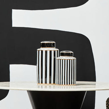 Modern interior with black and gold table and chairs against a black and white abstract wall.
