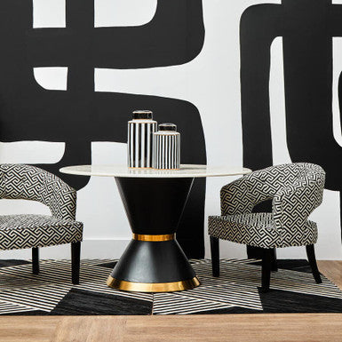 Modern interior with black and white patterned wall, black and gold table, and patterned chairs.
