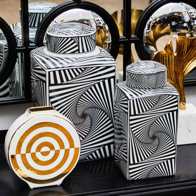Decorative vases with black and white geometric patterns on a reflective surface