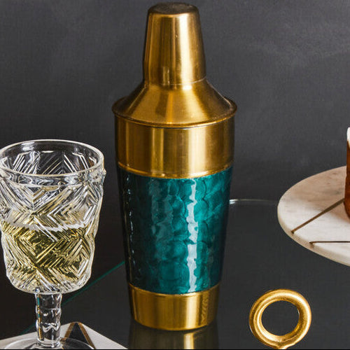 Set of cocktail glasses and a shaker on a dark surface with a black background
