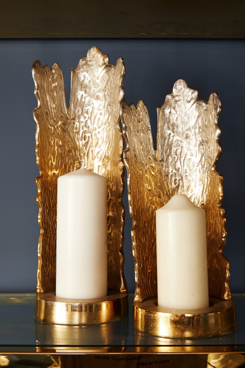 Decorative gold candle holders with white candles on a reflective surface.