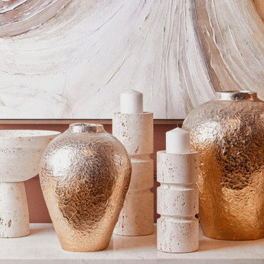 Decorative vases and candles on a surface with a marble wall background