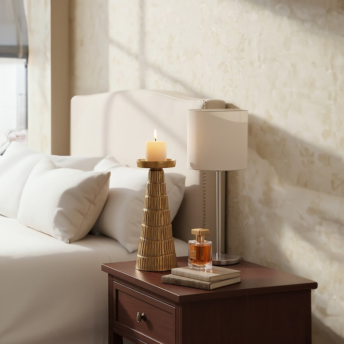 Nightstand with lamp, candle, and perfume bottle in a bedroom setting