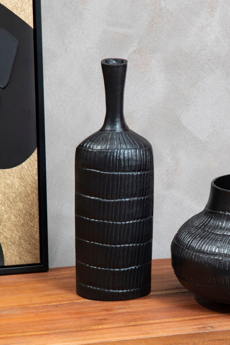 Black textured vase on a wooden surface with a neutral background