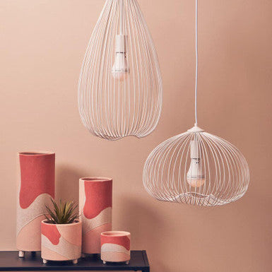 Wire mesh pendant lights with decorative vases on a pink background