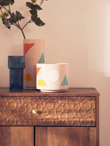 Three ceramic pots with geometric designs on a wooden surface.