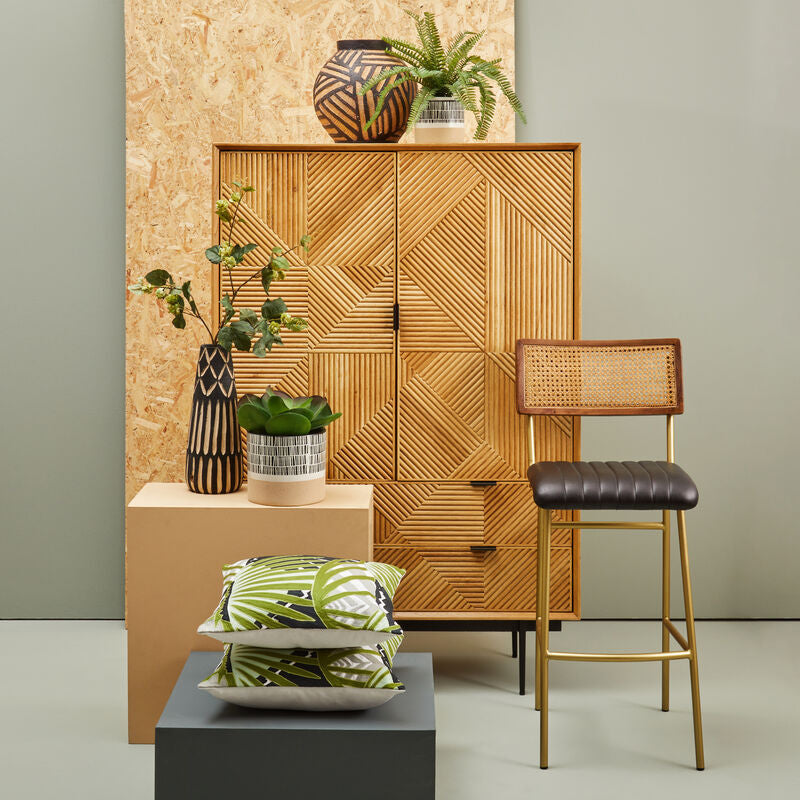 Wooden cabinet with decorative items and a bar stool in a room setting.