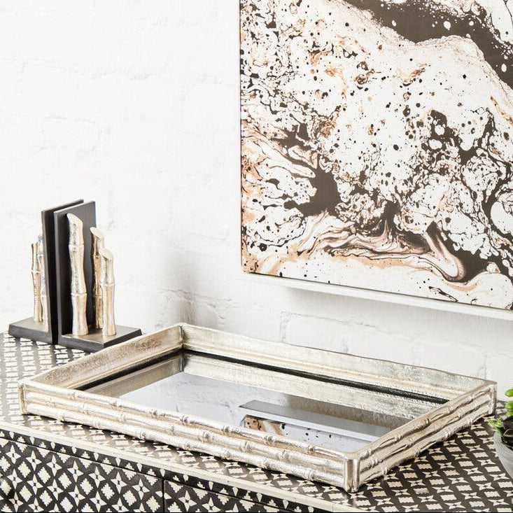 Decorative console table with a tray, books, and abstract art on a white wall.