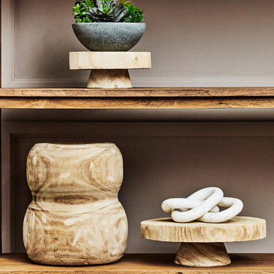 Decorative items including a potted plant, wooden stool, and white sculpture on a shelf.