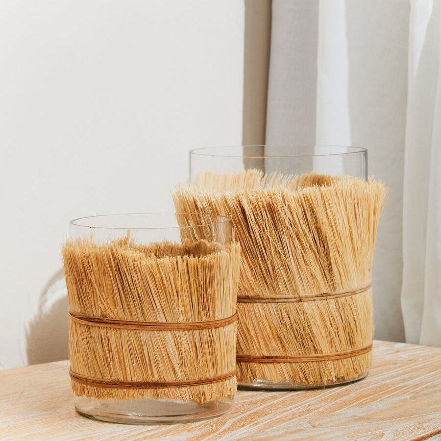 Two glass containers with straw-like tops on a wooden surface.