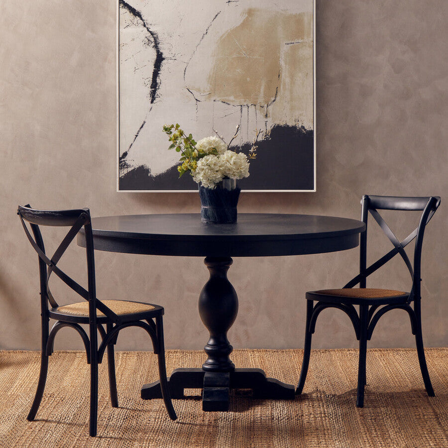 Round black table with two chairs in a room with abstract art on the wall.