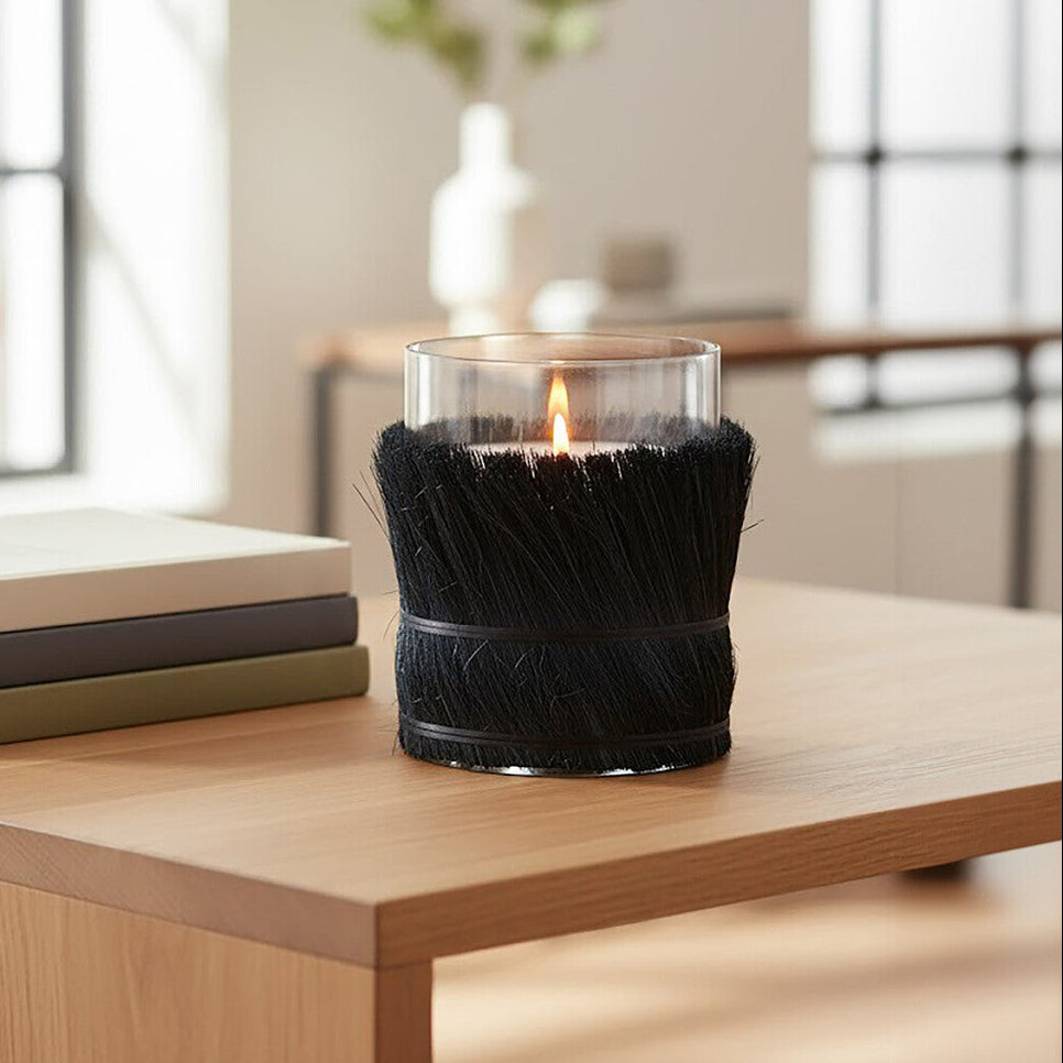 Candle in a decorative holder on a wooden surface with books and a blurred indoor background