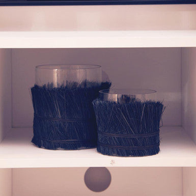 Two navy blue decorative vases on a white shelf with a striped background