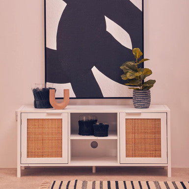 White cabinet with wicker doors against a wall with abstract art