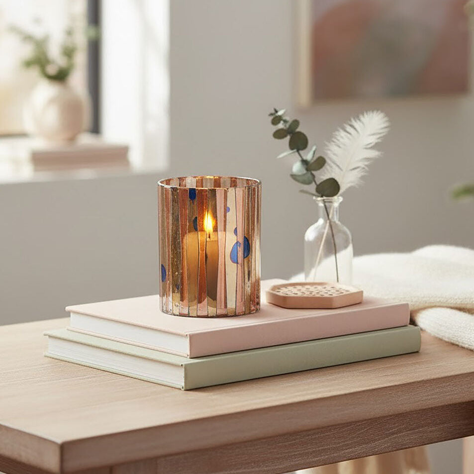 Decorative setup on a wooden table with books, a candle, and a vase.