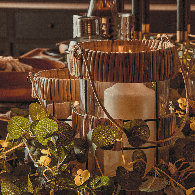 Decorative setup with candles, bottles, and greenery on a table.