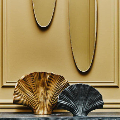 Decorative shell sculptures on a wooden console table with gold wall panels.
