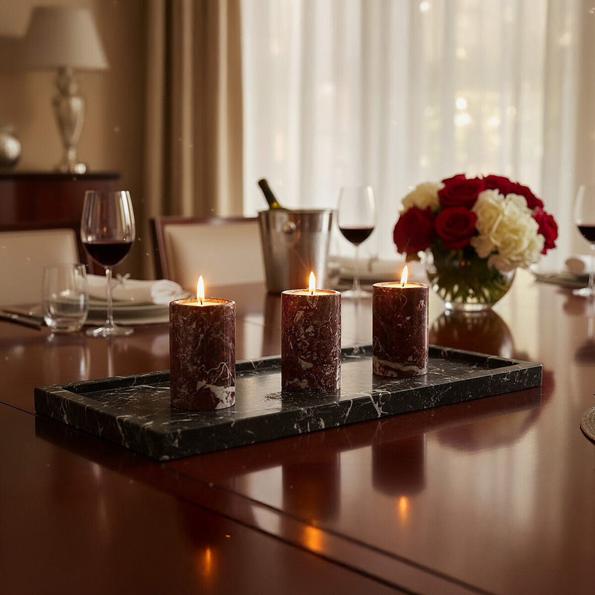 Candlelit dining table with candles, wine glasses, and flowers in a warm setting.