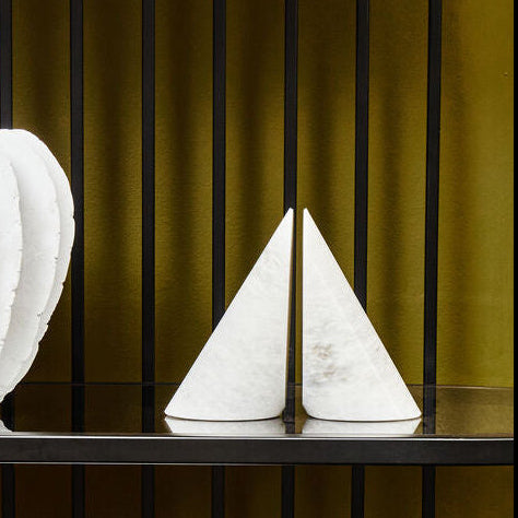 Decorative white vases and bowl on a black shelf against a green wall.
