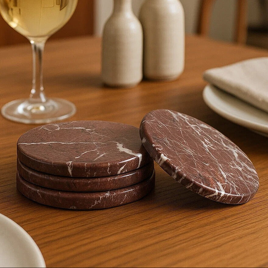 Marble-patterned coasters on a wooden table with a glass of white wine and decorative bottles.