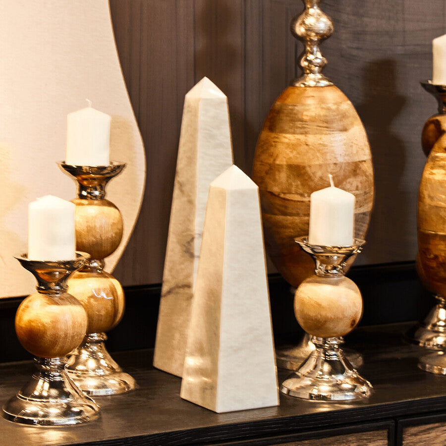 Decorative candles and obelisks on a dark surface with a neutral background