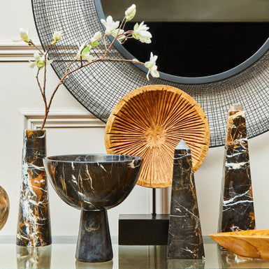 Decorative items including a black marble bowl, gold sculpture, and other decorative pieces on a glass table.