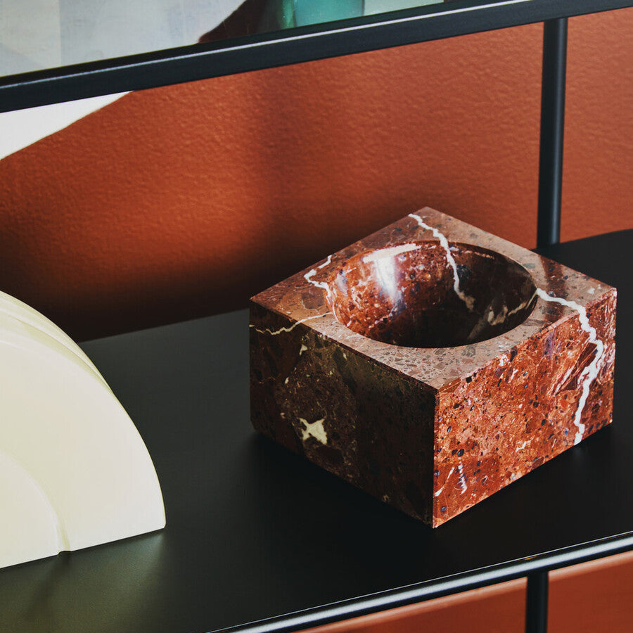 Marble-textured square object on a black surface with a blurred background