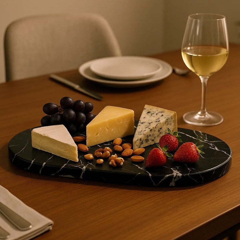 Platter of assorted cheeses, fruits, and nuts with a glass of white wine on a wooden table.