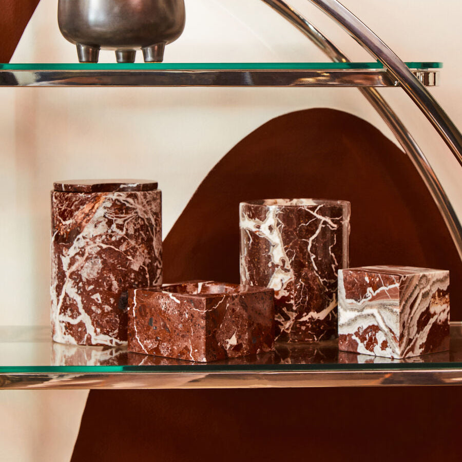 Marble-textured candle holders on a glass shelf with a blurred background