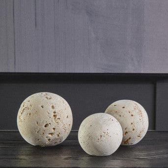 Three textured stone balls on a wooden surface with a dark background