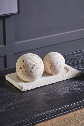 Two spherical bath bombs on a stone platter against a dark wall.
