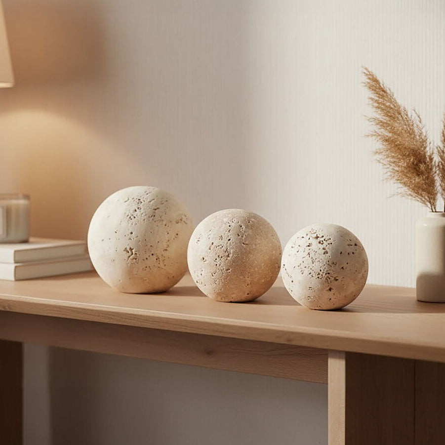 Decorative items on a wooden surface including spherical stone-like objects and a vase with dried plants.
