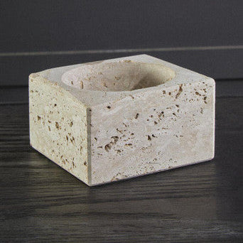 Square stone candle holder on a dark surface with a neutral background