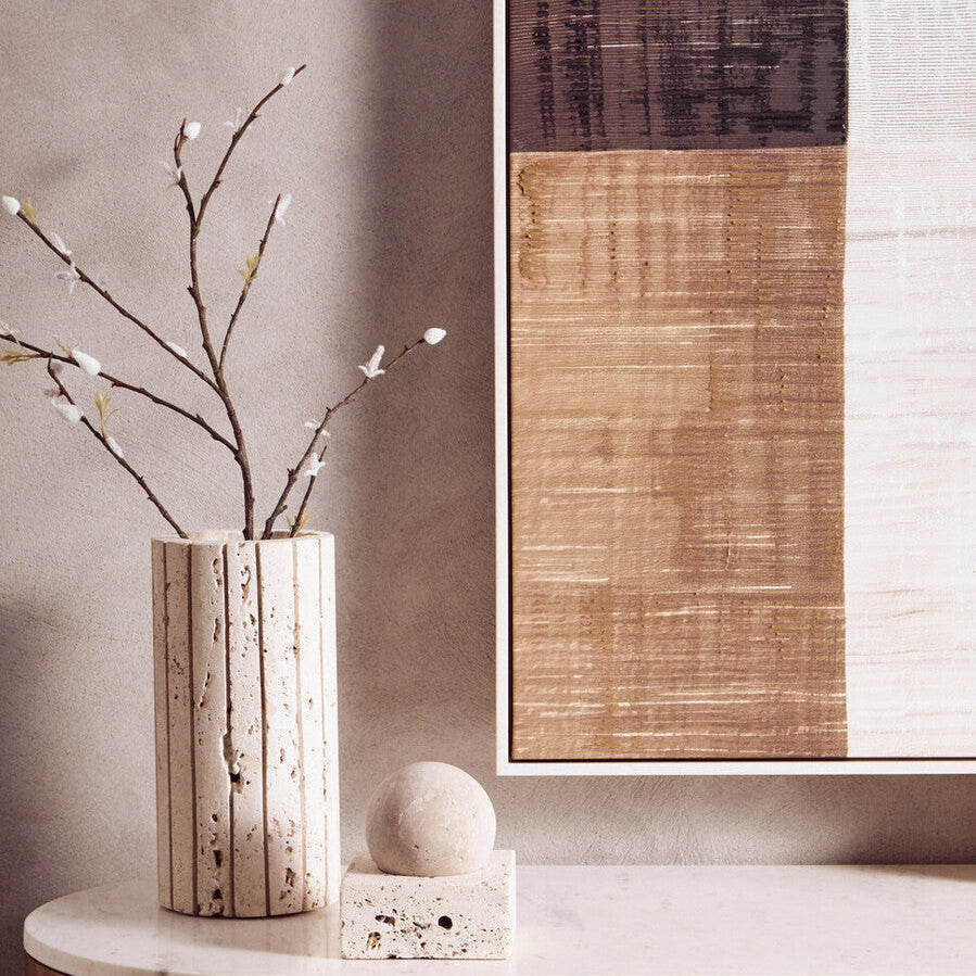 Decorative elements including a vase with branches, a sphere, and a framed abstract painting on a neutral wall.