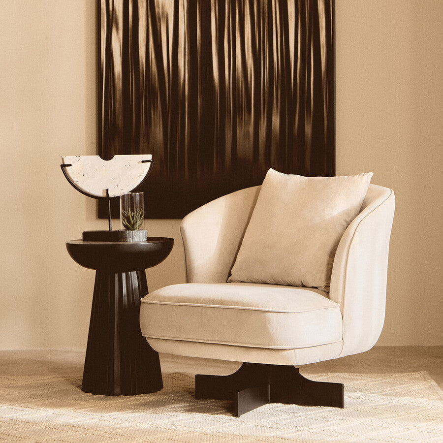 Beige armchair with a side table and abstract painting in a room.