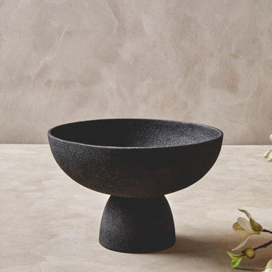 Black ceramic bowl on a light wooden surface with a neutral background