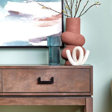 Wooden console table with decorative items against a light green wall
