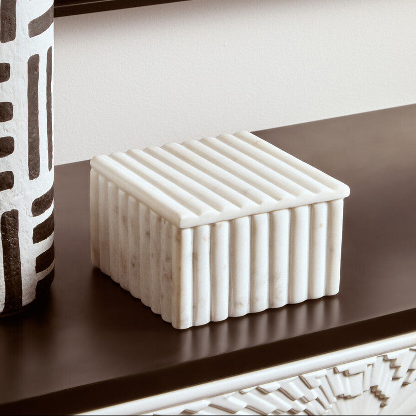 Decorative box with textured surface on a shelf next to a vase