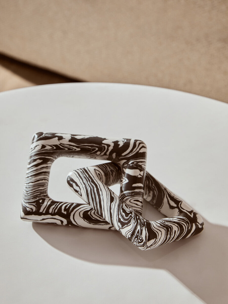 Marbled patterned hair scrunchie on a white surface with a beige background